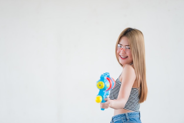 Mujer sexy asiática con agua de pistola en la mano sobre fondo blancoDía del festival songkran en tailandiaLo mejor del festival de tailandiaTierra de la sonrisa