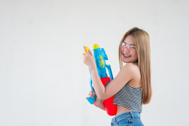 Mujer sexy asiática con agua de pistola en la mano sobre fondo blancoDía del festival songkran en tailandiaLo mejor del festival de tailandiaTierra de la sonrisa