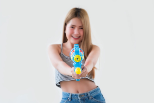 Mujer sexy asiática con agua de pistola en la mano sobre fondo blancoDía del festival songkran en tailandiaLo mejor del festival de tailandiaTierra de la sonrisa