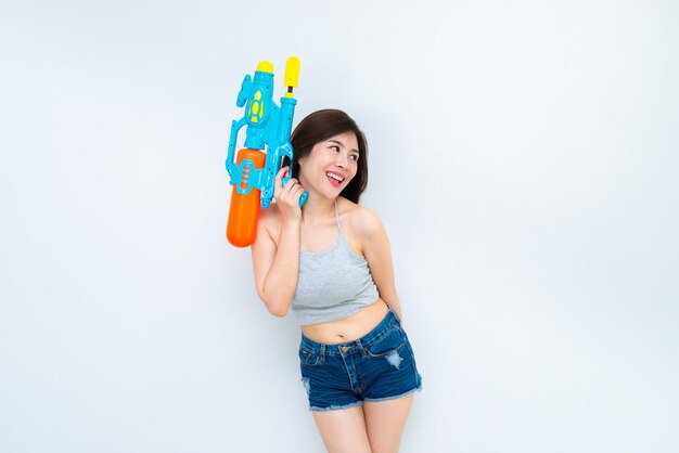 Mujer sexy asiática con agua de pistola en la mano sobre fondo blancoDía del festival songkran en tailandiaLo mejor del festival de tailandiaTierra de la sonrisa