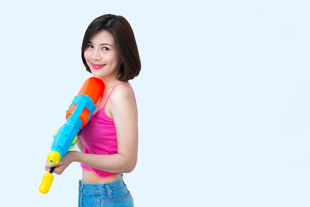 Mujer sexy asiática con agua de pistola en la mano sobre fondo blancoDía del festival songkran en tailandiaLo mejor del festival de tailandiaTierra de la sonrisa