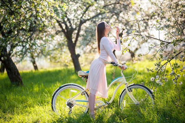 Mujer sexy con una bicicleta en un jardín de primavera