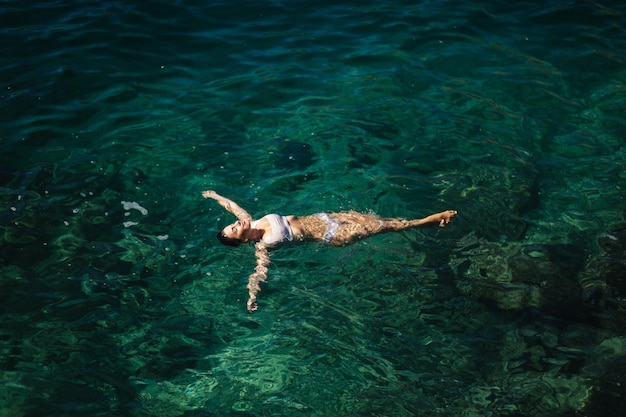 Mujer sexy en bikini acostada en el agua atractiva joven disfrutando del sol de verano hermosa laguna