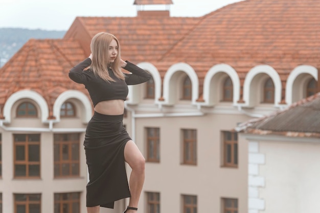 Mujer sexy caminando sobre fondo de arquitectura antigua Mujer joven con estilo en ropa negra en la calle