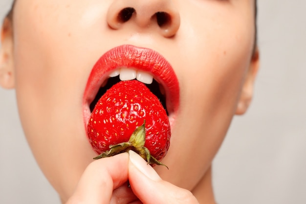 Mujer sexy comiendo fresa. Labios sensuales.