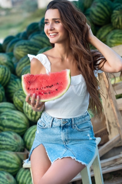 Foto mujer sexy comiendo sandía fresca en el campo de sandía. verano.