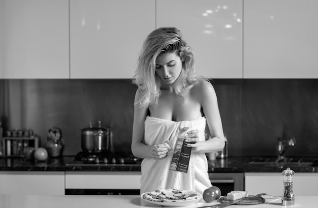 Mujer sexy cortando ingredientes para pizza, queso y salchichas, mujer hermosa sexy preparando la mañana