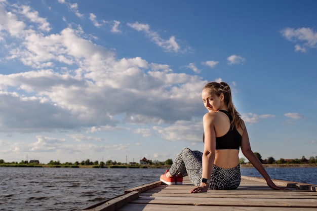 Mujer sexy deportiva en ropa deportiva en el muelle en el fondo del agua