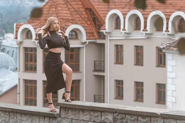 Mujer sexy joven caminando sobre fondo de arquitectura antigua Mujer elegante en traje negro y tacones