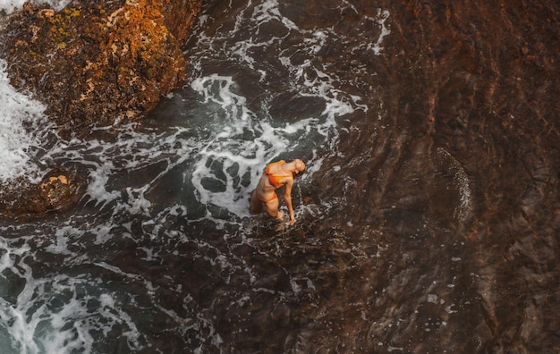 Mujer sexy en el mar cerca de las olas vista superior tiro aéreo