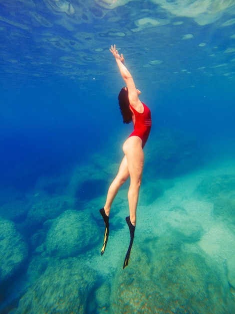 Mujer sexy nadando bajo el agua en máscara de buceo con aletas vacaciones de verano