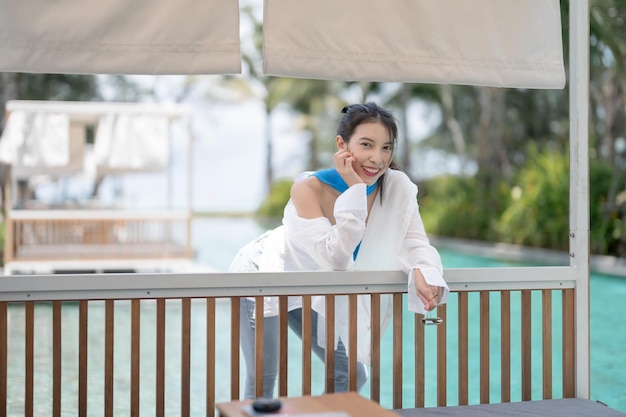 Mujer sexy relajándose cerca de la cabaña de hamacas junto a la piscina en el hotel resort