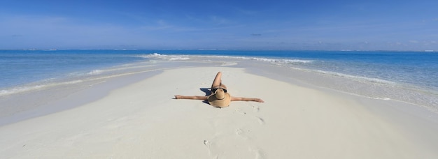 mujer sexy en un sombrero de paja se encuentra en la arena del mar