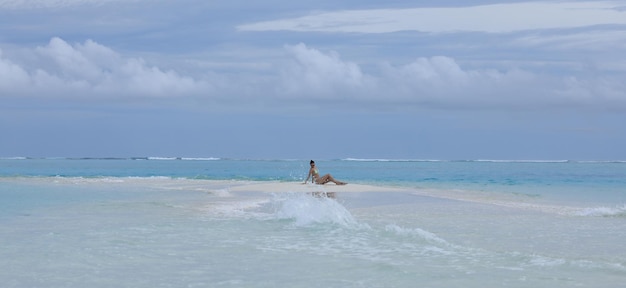 mujer sexy en un sombrero de paja se encuentra en la arena del mar