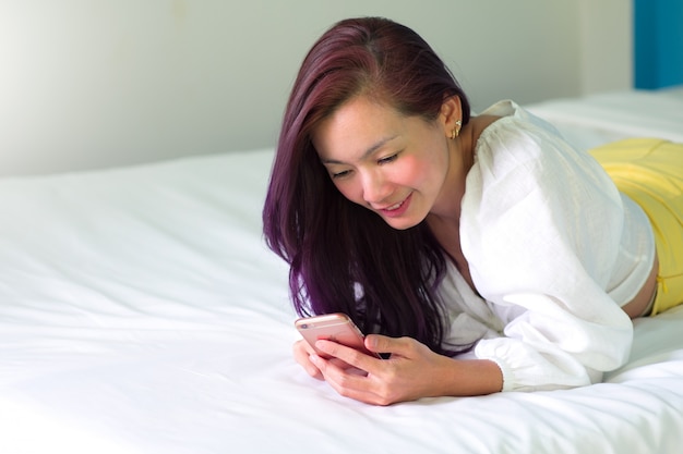 Mujer sexy con un teléfono inteligente en la cama.