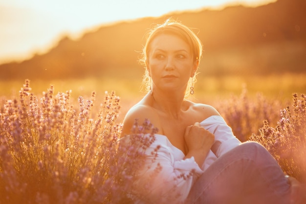 Una mujer se sienta en un campo de lavanda.