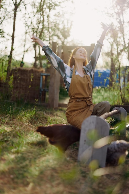 Foto una mujer se sienta en el corral de pájaros y alimenta a los pollos con alimentos orgánicos frescos y saludables para la seguridad y la salud de los pájaros en la granja en un soleado día de verano al atardecer