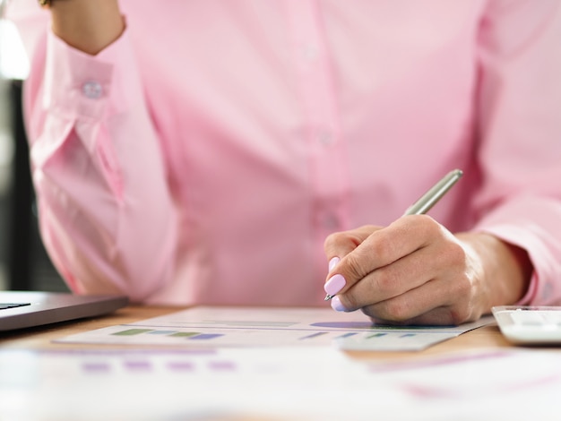 La mujer se sienta en el lugar de trabajo y toma notas en el gráfico