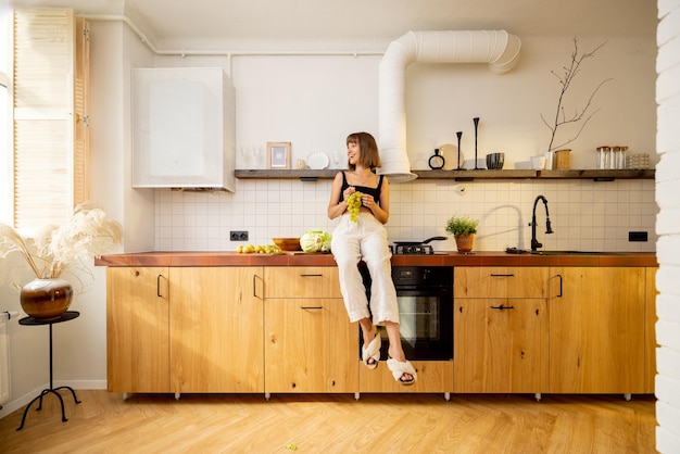 La mujer se sienta en la mesa de la cocina con comida saludable en casa