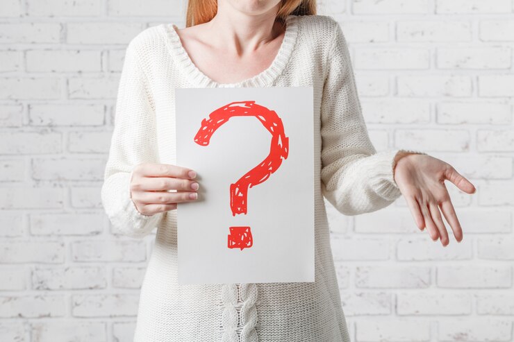 Foto mujer con signos de interrogación sobre fondo gris
