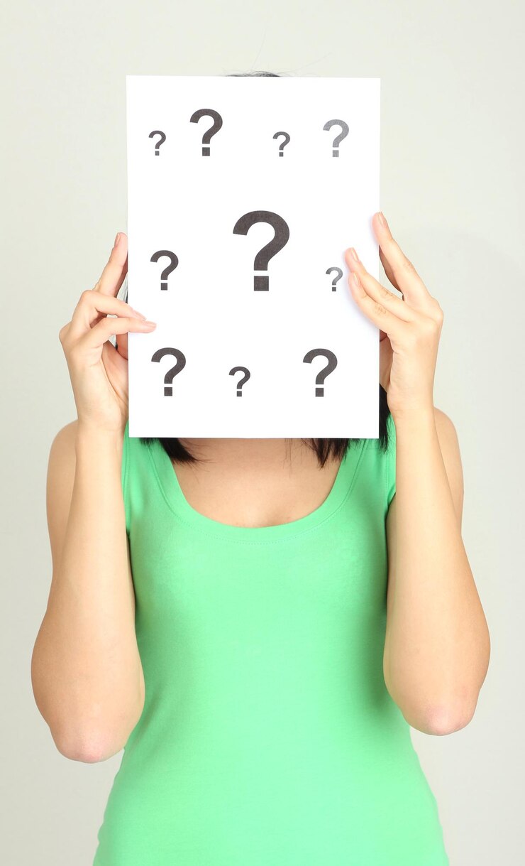 Foto mujer con signos de interrogación sobre fondo gris