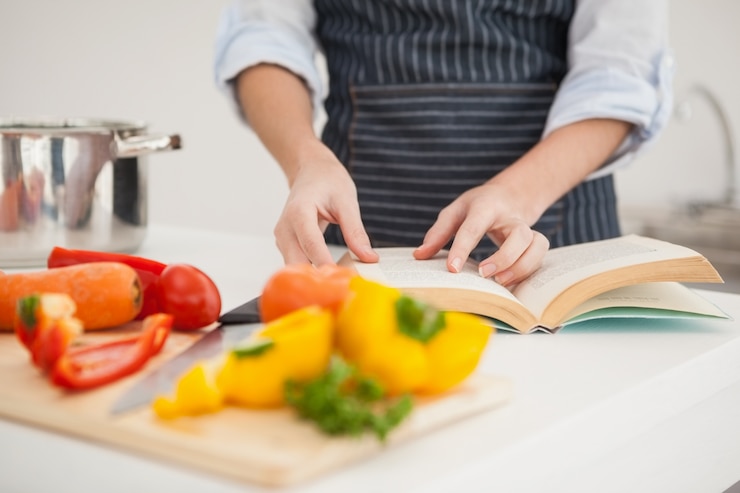 Foto mujer siguiendo una receta en el libro