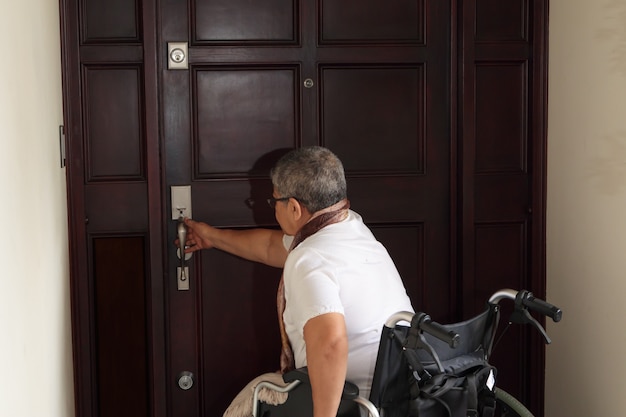 Mujer en silla de ruedas abriendo la puerta