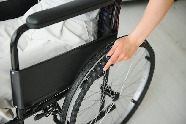 Mujer en silla de ruedas con la mano en la rueda de cerca