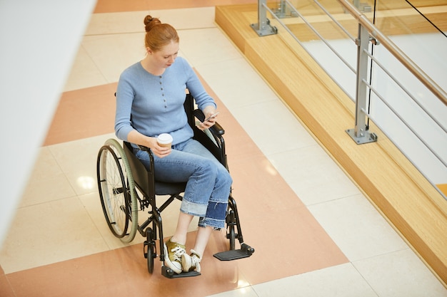 Mujer en silla de ruedas trabajando en línea por teléfono