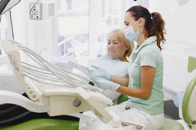 Una mujer en un sillón dental con un dentista con mascarilla y guantes.