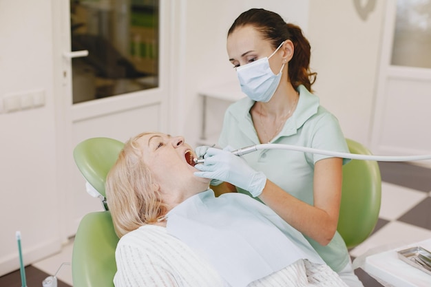 Una mujer en un sillón dental con un dentista con mascarilla y guantes.