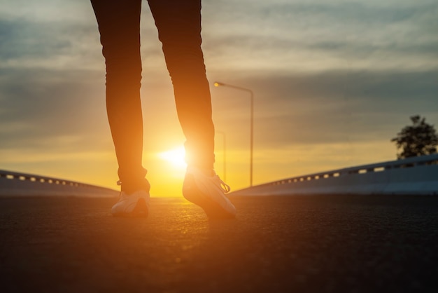 Mujer de silueta caminando por la calle al atardecer.