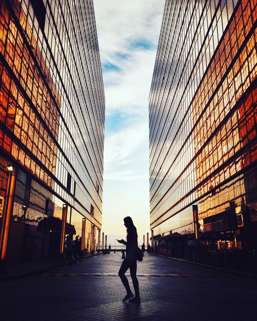 Foto mujer silueta caminando por la calle contra edificios en la ciudad