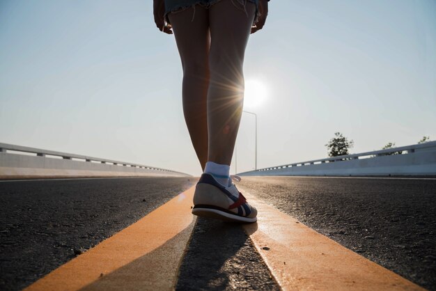 Mujer de silueta caminando por la calle en la puesta de sol.