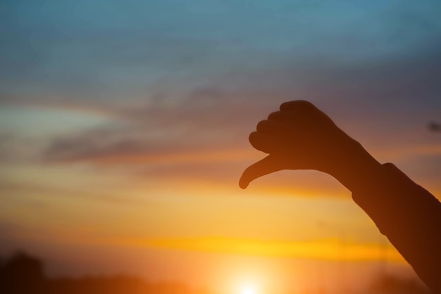 Mujer de silueta contratando mal al atardecer en la carretera.