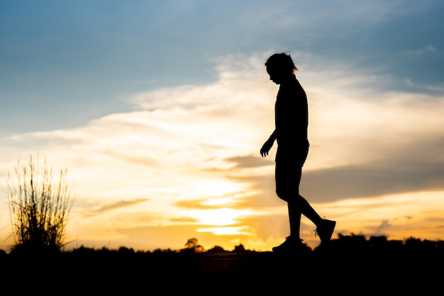 Mujer de silueta corriendo sola al hermoso atardecer en el parque.