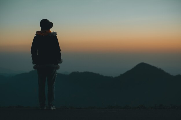 Mujer de silueta triste en la montaña en filtro de puesta de sol y vintage