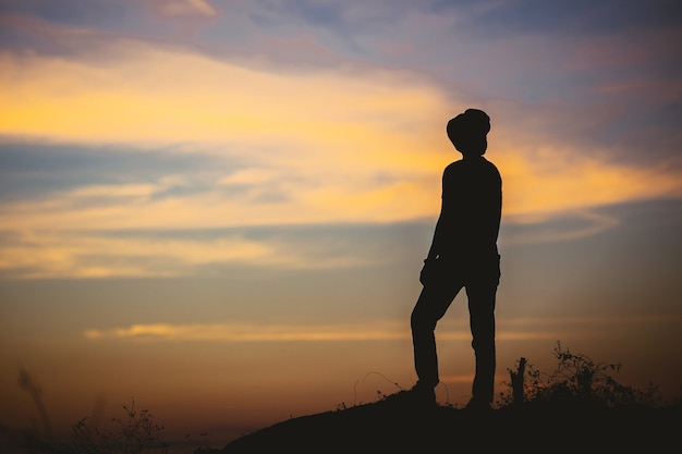 Mujer de silueta triste en la montaña en filtro de puesta de sol y vintage