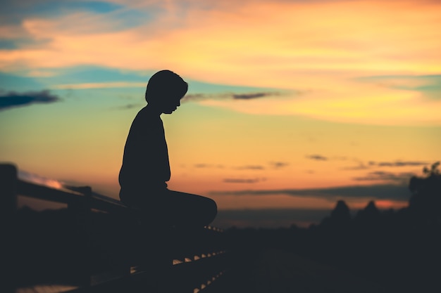 Mujer de silueta con tristeza al atardecer solo.