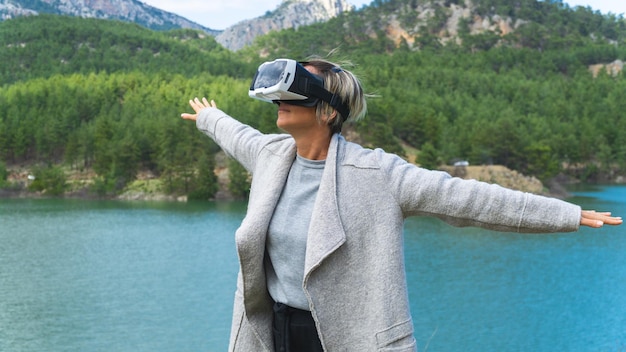 Mujer con un simulador de realidad virtual contra montañas y cielo