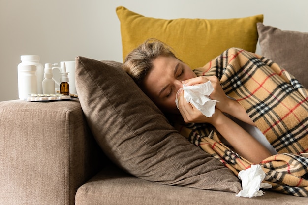 Mujer con un síntoma de secreción nasal debajo de la manta en casa