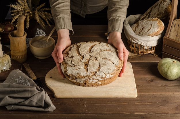 Una mujer sirve delicioso pan de centeno integral recién horneado.