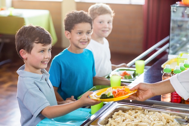 Mujer sirviendo comida a escolares sonrientes