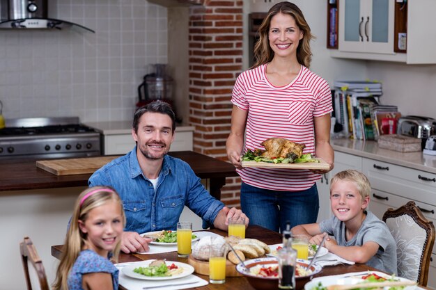 Foto mujer sirviendo comida a su familia en la cocina