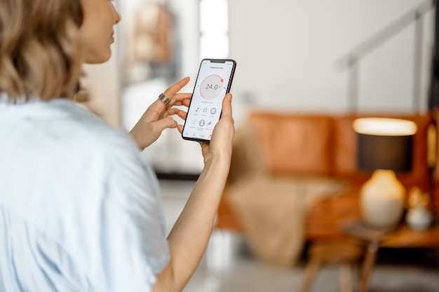 Foto mujer con smartphone con aplicación lanzada para ajuste de temperatura del aire, monitoreo de la calidad del aire. microclima de salud en el concepto de hogar.