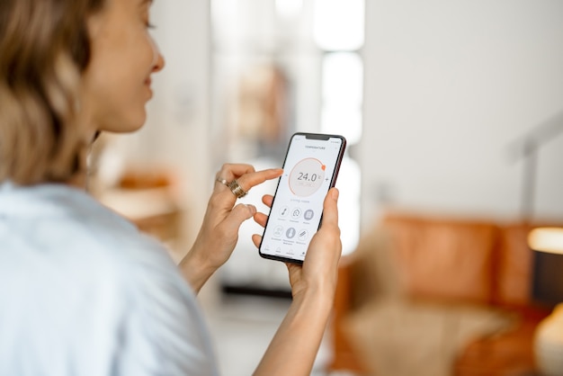 Mujer con Smartphone con aplicación lanzada para ajuste de temperatura del aire, monitoreo de la calidad del aire. Microclima de salud en el concepto de hogar.