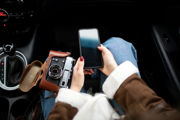 Foto mujer con smartphone en el coche durante un viaje por carretera de invierno