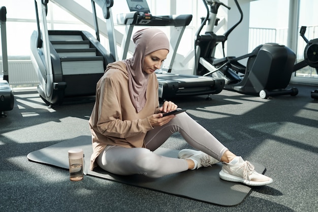 Mujer con smartphone en gimnasio