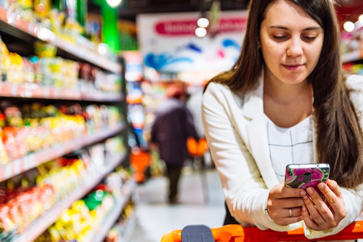 Foto mujer con smartphone en tienda. compras de comestibles. gadgets y compras.
