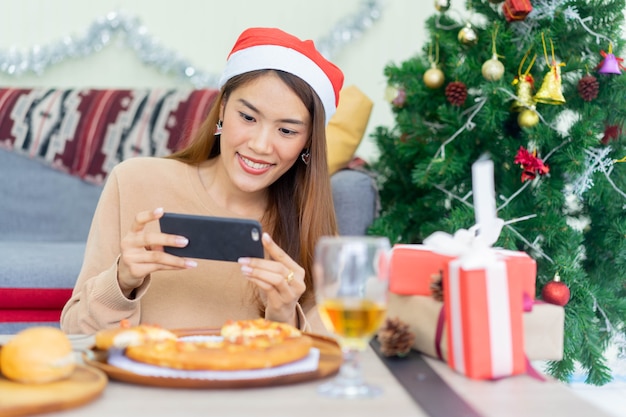 Mujer con smartphone para tomar una foto de la comida del almuerzo para el festival de Navidad y el concepto de celebración